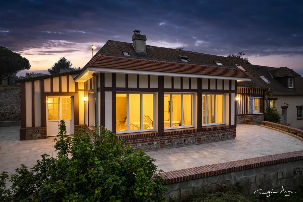 Extension contemporaine intégrée à une maison normande, grandes ouvertures