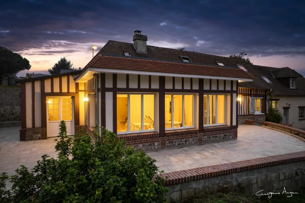 Extension contemporaine intégrée à une maison normande, grandes ouvertures